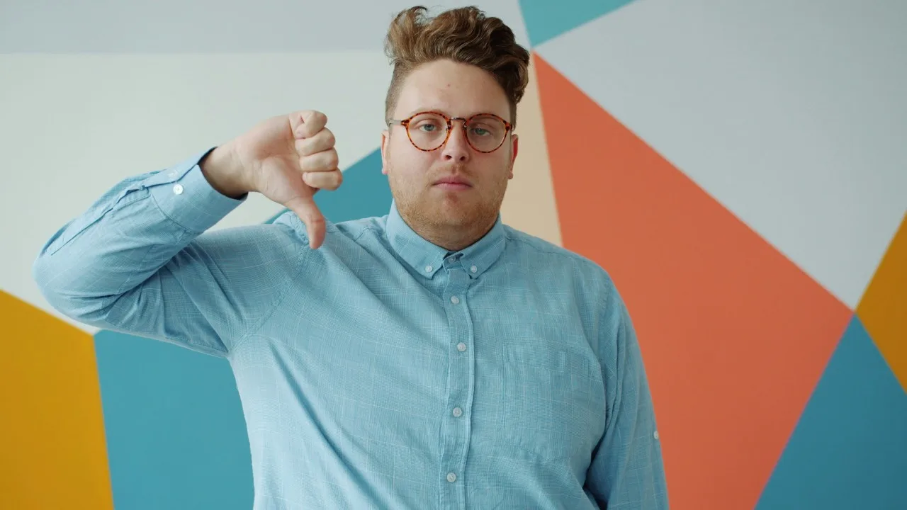 A man giving a thumbs-down against a colorful geometric wall